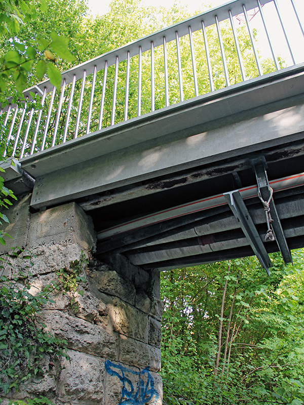 Bewehrt mit 14.5 kg Carbon und einem Gewicht von nur 3200 kg (exklusive Geländer) stülpt sich die neue Eulachbrücke über die bestehenden Stahlträger, an denen Werkleitungen hängen.