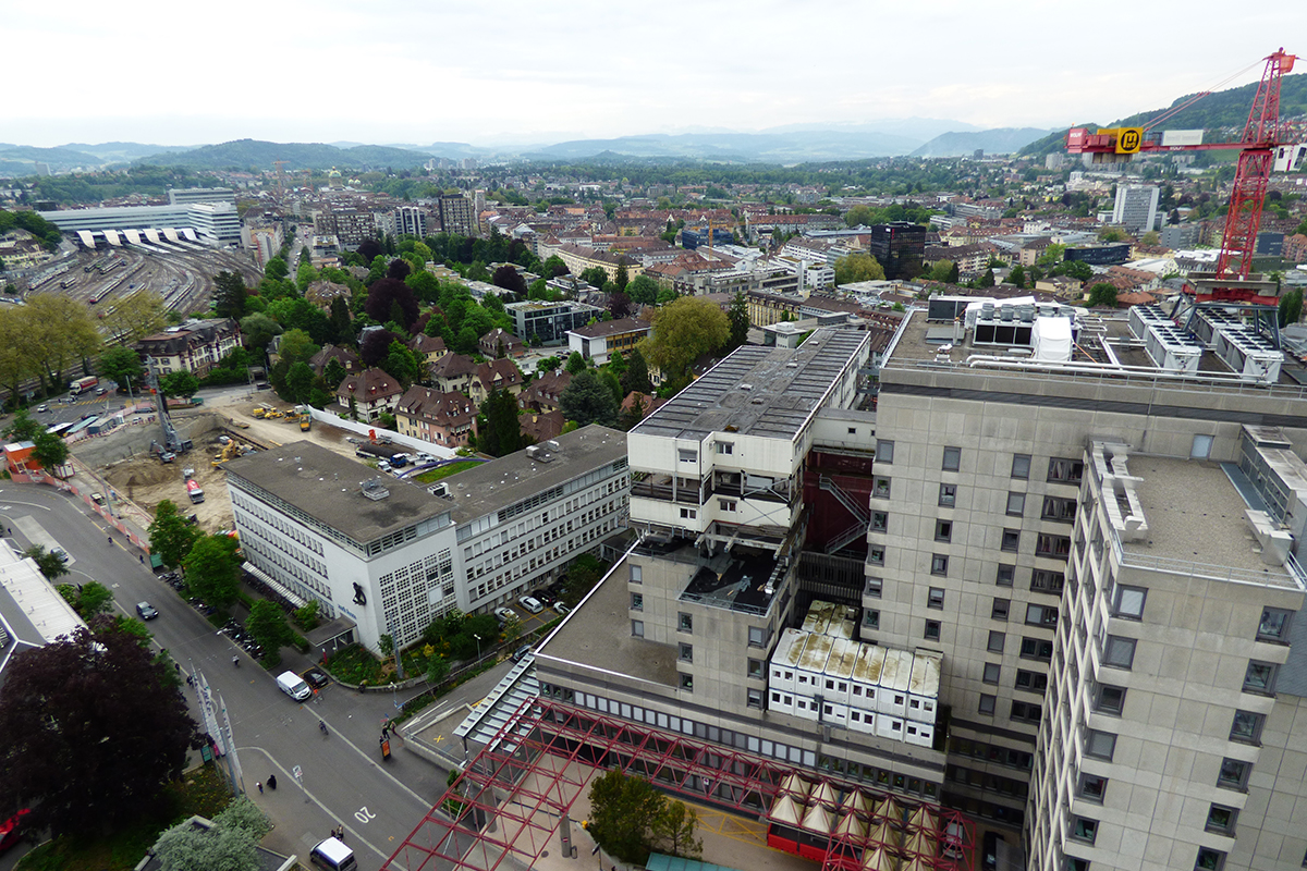 Blick vom Bettenhochhaus auf Bern mit Hauptbahnhof (links), Haupteingangsbereich (unten) und Kinderklinik (gegenüber). Die Kinderklinik wurde etagenweise saniert. Dieses Vorgehen wird für das Bettenhochhaus ausgeschlossen. Es wird abgerissen werden.