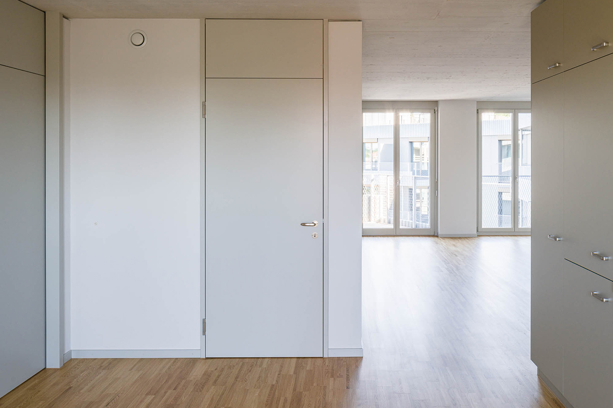 Ansicht einer Wohnung in der städtischen 2000-Watt-Siedlung Stöckacker Süd in Bern (Lüftungsvariante B/C). Der Durchlass neben der Nasszellentür ermöglicht das Einströmen von frischer Zuluft, die ihrerseits zentral pro Wohneinheit gefasst wird.