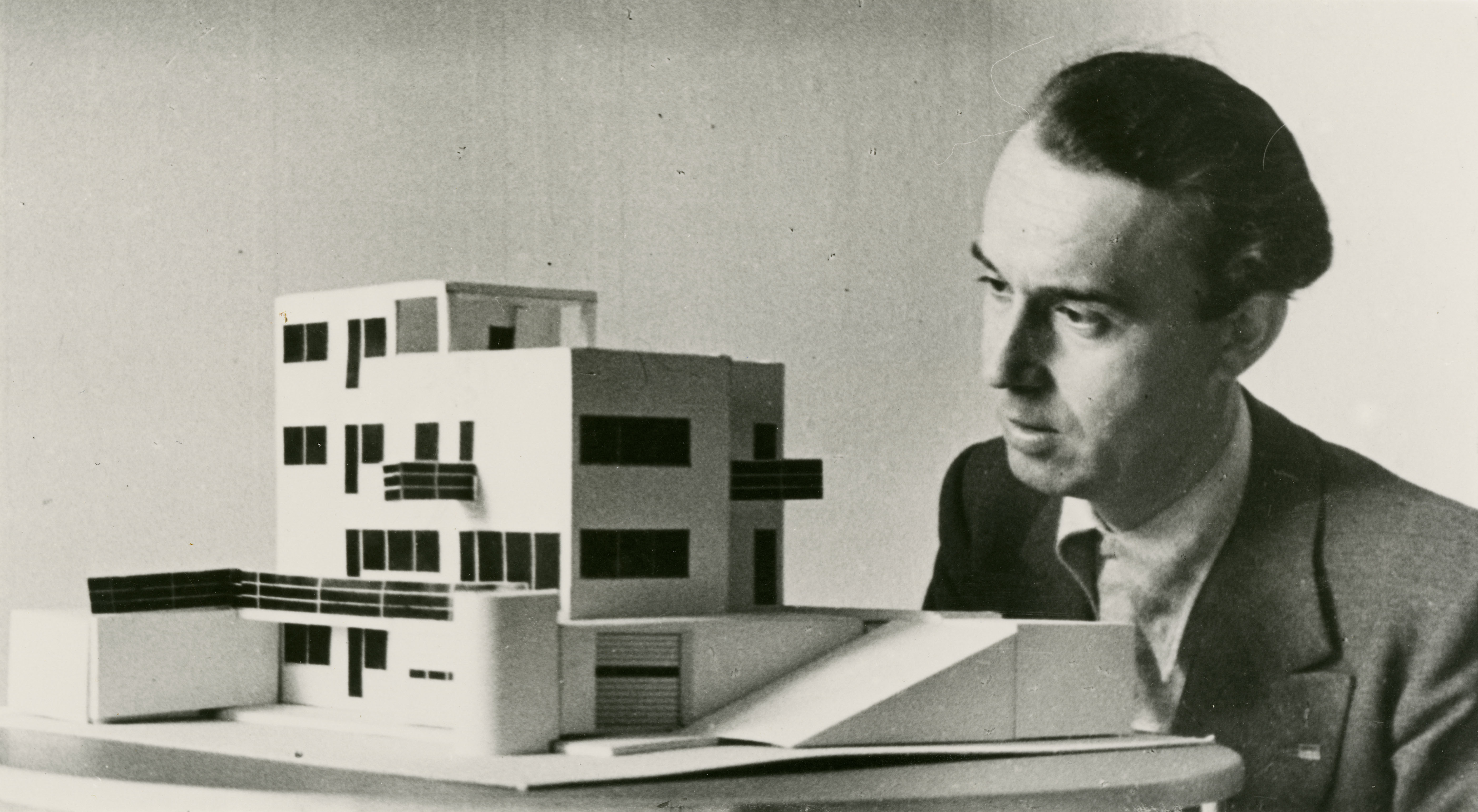 Alberto Sartoris, portrait avec la maquette de la maison pour Roman Brum en 1934, s.d. Tirage monochrome sur papier argentique, reproduction. Sartoris a toujours privilégié le travail direct de l’architecte, aidé parfois de ses élèves. « Je pense qu’un architecte doit pouvoir se faire aider par des équipes [ ] mais il doit concevoir son œuvre, il doit la dessiner avec ses élèves ou avec ses collaborateurs directs, alors que les architectes d’aujourd’hui, ce sont des chercheurs de travaux,