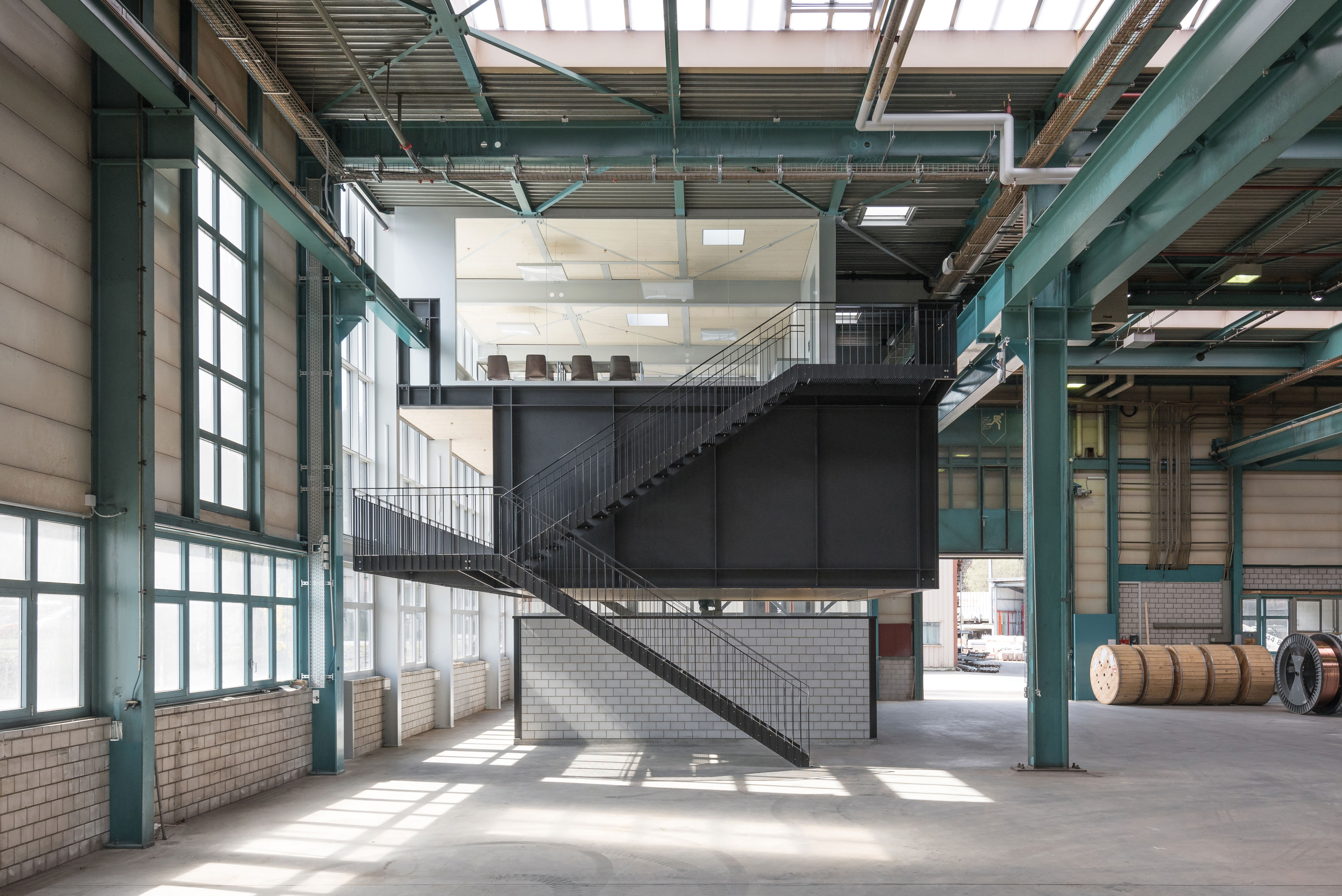 Locaux sociaux pour un atelier, Gwatt (projet gagnant) En association avec les ingénieurs de Tragstatur, l’agence Furrer Jud Architekten a inséré une construction métallique mixte dans l’ossature d’un bâtiment existant. L’espace central de cet ensemble de trois niveaux est réalisé sous la forme de volumes métalliques. Les deux joues métalliques étirent l’espace dans le sens transversal. Dans le sens longitudinal, le contreventement du caisson est garanti par un effet de cadre.