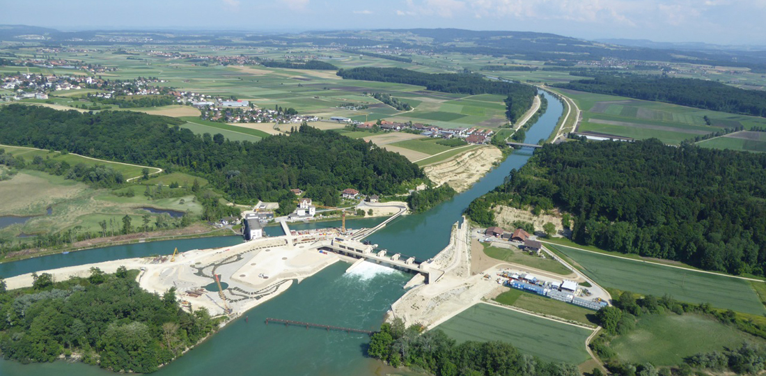 Das neue Kraftwerk Hagneck bei der Mündung der Aare in den Bielersee. Gleich dahinter der Hagneckeinschnitt mit dem abgetragenen Fels auf der linken Seite in Blickrichtung (ocker gefärbte Stelle zwischen Wald und Brücke).