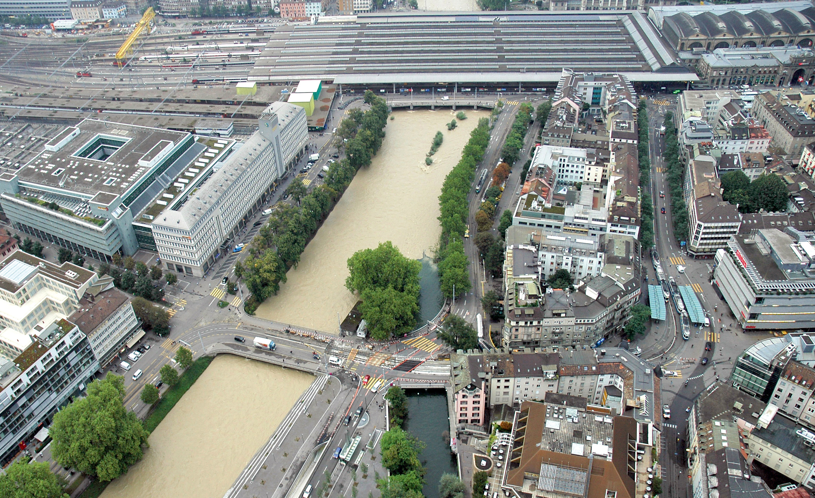 Hochwasser 2005: Die Sihl fliesst zuerst unter der Gessnerbrücke und dann unter dem Zürcher Hauptbahnhof hindurch. Das lang­gezogene Gebäude am linken Ufer ist die Sihlpost