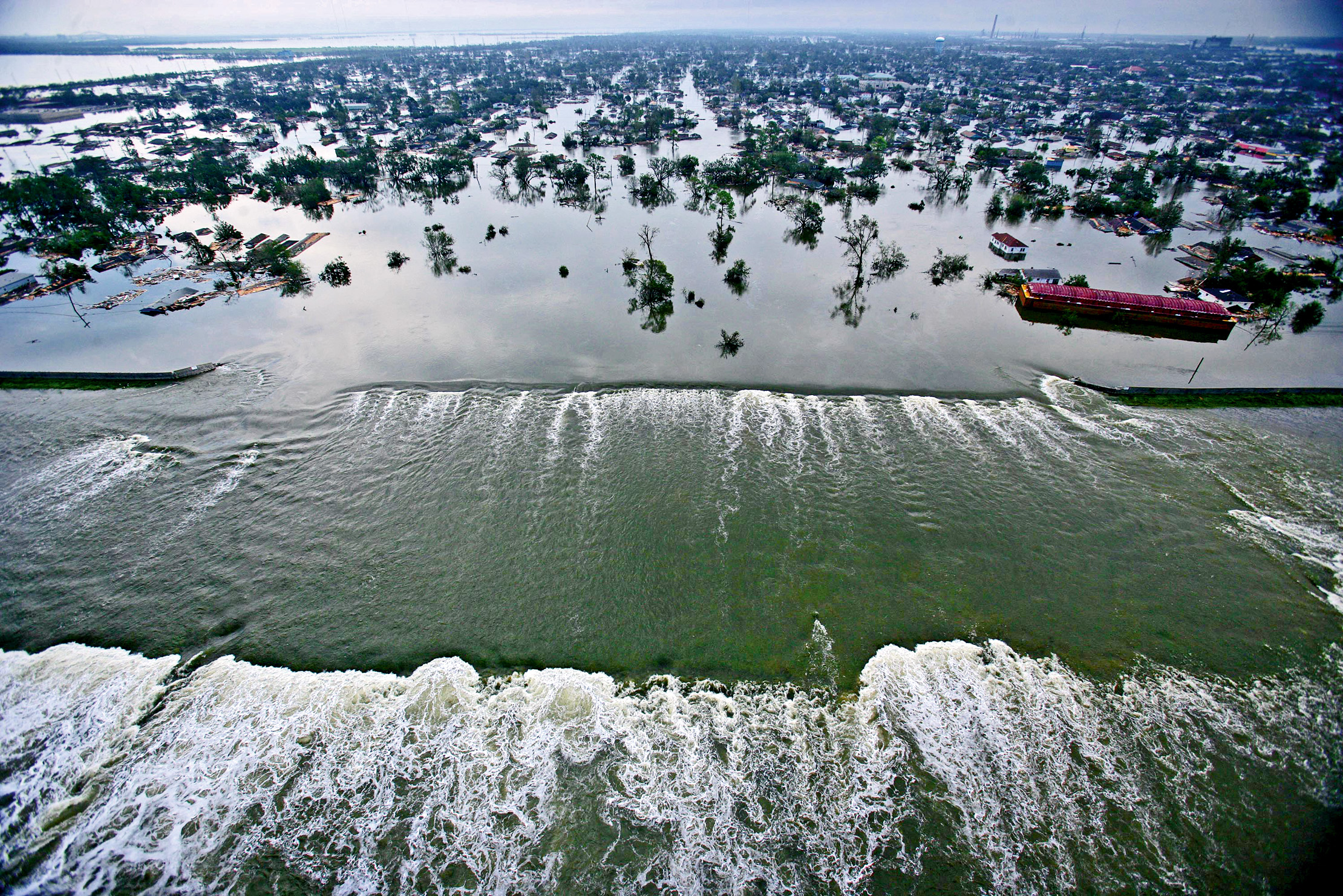 Am 30. August 2005, dem Tag nach Katrina, strömt das Wasser aus dem Lower Ninth Ward durch den gebrochenen Damm zurück in den Industriekanal