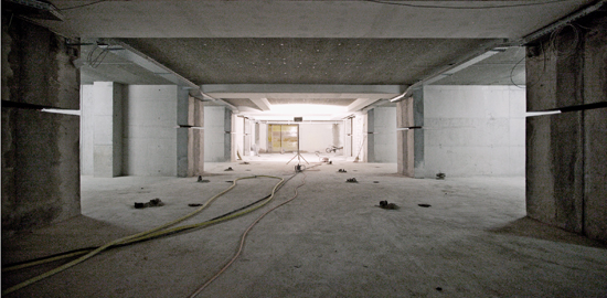 Die grosszügige Tiefgarage im Untergeschoss entstand durch den Abbruch der tragenden Wände von 25 kleinteiligen Zivilschutzräumen. Der eigentümliche Schlitz auf halber Wandhöhe ist eine konstruktive Massnahme zur Verbesserung der Krafteinleitung in die Bo