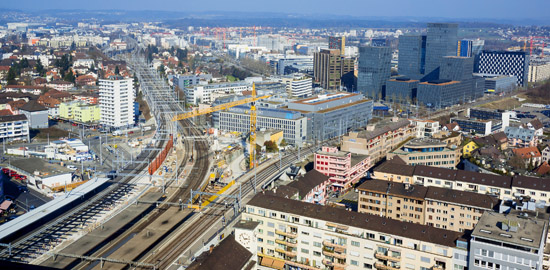Oerlikon wird von einem breiten Schienenstrang geteilt, Richtung Nordosten verzweigt er sich. Links im Bild die Linie nach Schaffhausen, dem Flugplatz und der Ostschweiz, rechts diejenige über Wallisellen nach Winterthur. Der laufende Um- und Ausbau des B