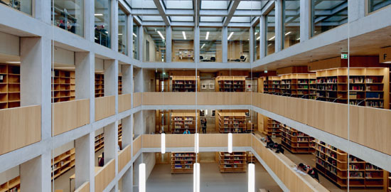 Die Mediathek bildet das geistige und räumliche Zentrum der Hochschule. In sich gekehrt wirkt sie wie ein überdachter Platz. Die Büchertürme zitieren die Pfeiler der Stiftsbibliothek im Kloster St.?Gallen und scheinen die Geschossplatten zu tragen. (Foto: