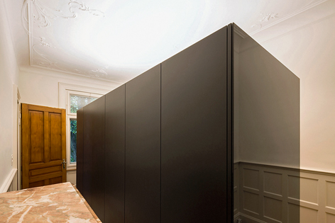 Der schwarze Kleiderschrank füllt beinahe das Zimmer mit der frei geformten Stuckatur. (Foto: Hanspeter Schiess)