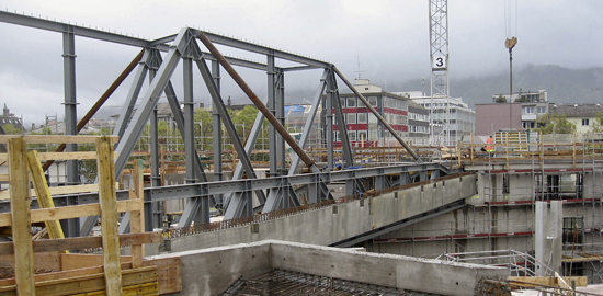 Baustelleneindruck: Links die ein- und dreigeschossigen Fachwerkträger der «Wohnbrücke» über der Tramhallenausfahrt. Parallel dazu der erste vorfabrizierte Betonhauptträger des Tramhallendachs mit den Aussparungen für die Sekundärträger. Rechts die Mittel