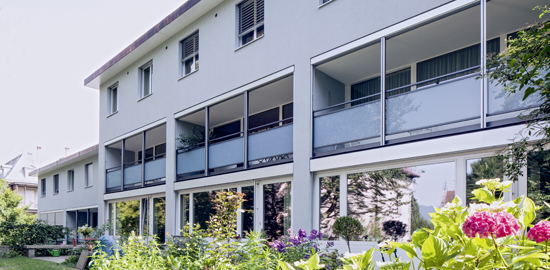 Wohnhaus Riesbach-Quartier: Neue Glasbrüstungen begrenzen die Loggien. Fensterlaibungen im Obergeschoss; Dachvorsprung und Zwischenwände der Loggien zeichnen mit 14cm Isolationsschicht die Gebäudestruktur stärker nach als zuvor. (Foto: Nina Mann)
