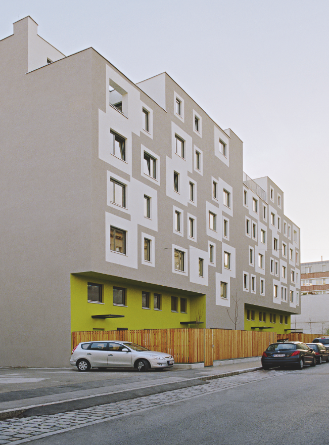 Wohnbau Rauchfangkehrergasse, Wien, 2008: Der geringe Öffnungsanteil der Fassade soll durch die Umrandung der Fenster mit Farbfeldern optisch vergrössert werden. Sowohl Fenster als auch Faschen haben unterschiedliche Formate und sind unregelmässig angeordnet ein sehr unruhiges, aufgeregtes Fassadenbild. Die Farbflächen sind weder strukturell gedacht, noch wollen sie klassische Architekturelemente zitieren. Im Sockelbereich, wo das Gebäudevolumen zurück­springt, markiert ein kräftiges Grün die Einsc
