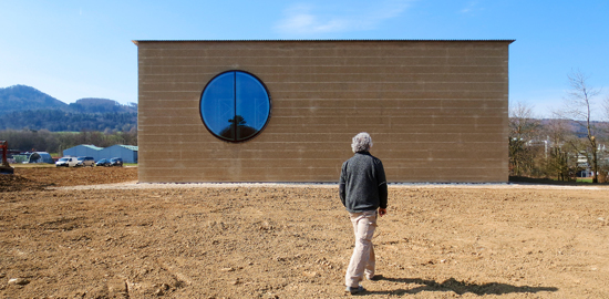 Für das neue Kräuterzentrum von Ricola hat Martin Rauch die Vorfertigung perfektioniert. Das Material der Fassaden stammt aus der unmittelbaren Umgebung: Ton in Ton ragt das Haus kurz vor seiner Vollendung aus dem noch unbestellten Acker. (Foto: Marko Sau