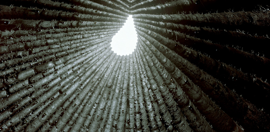Aufnahme der offenen Spitze in der Bruder-Klaus-Kapelle, Wachendorf bei Mechernich, Deutschland (Peter Zumthor, 2007). Im Bild sind die Löcher der Verschallungsgerüsten zu sehen, in denen Glashalbkugeln glitzern. Die Innenwände wurden mit einem Köhlerfeuer geräuchert
