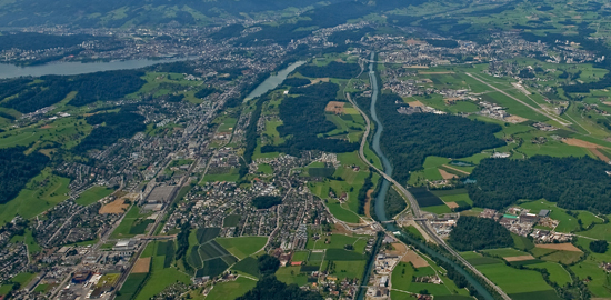 Zersiedelung beim Autobahnanschluss von Buchrain LU. Links oberhalb der Mitte Luzern mit einem Teil des Vierwaldstättersees und dem Rotsee. (Foto: Reportair.ch)